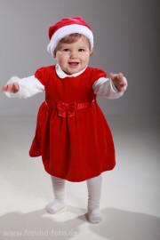 Baby im roten Outfit läuft zum ersten mal im Fotostudio