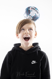 Junge jongliert Ball auf seinem Kopf