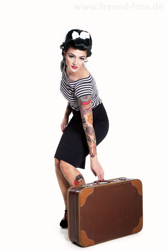 Frau im sexy Pinup Outfit mit alten Reisekoffer